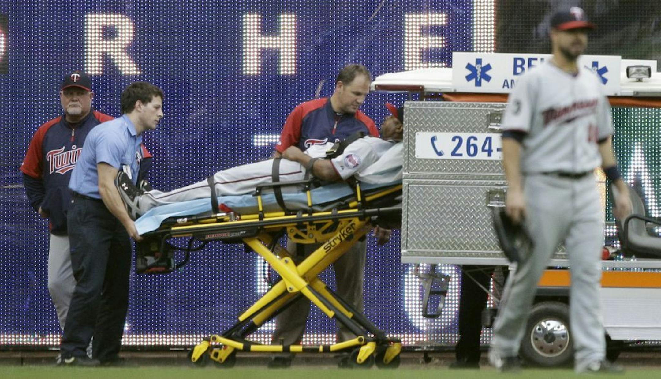 Minnesota Twins manager Ron Gardenhire, left, watches as left fielder Delmon Young is taken off the field after Young ran into the wall on a ball hit by Milwaukee Brewers' Yuniesky Betancourt during the fifth inning of a baseball game Saturday, June 25, 2011, in Milwaukee. Young left the game.