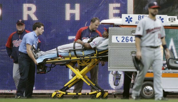 Minnesota Twins manager Ron Gardenhire, left, watches as left fielder Delmon Young is taken off the field after Young ran into the wall on a ball hit 