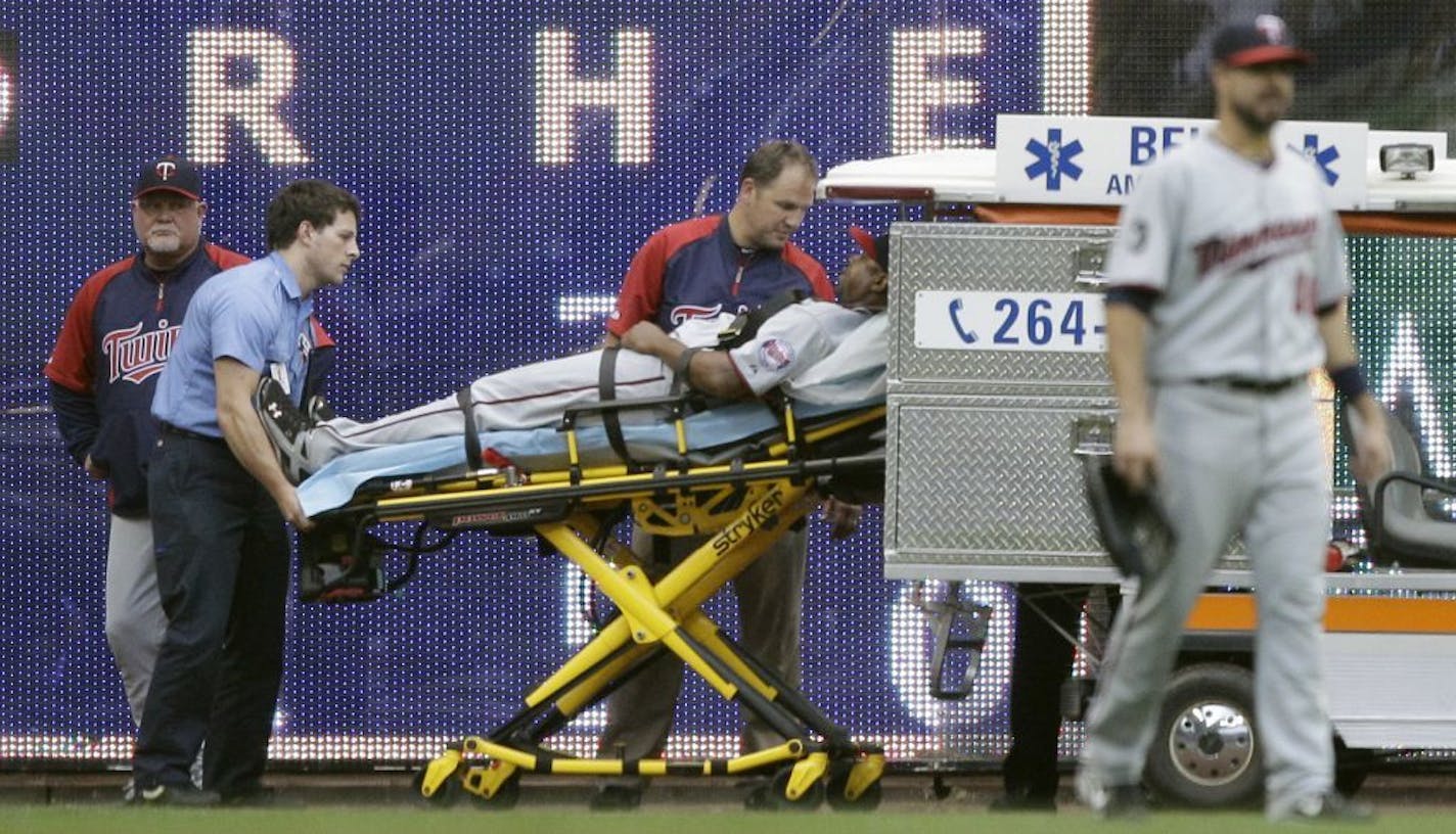 Minnesota Twins manager Ron Gardenhire, left, watches as left fielder Delmon Young is taken off the field after Young ran into the wall on a ball hit by Milwaukee Brewers' Yuniesky Betancourt during the fifth inning of a baseball game Saturday, June 25, 2011, in Milwaukee. Young left the game.