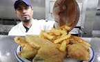 Cook Alvaro Aguilera adds french fries to a plate of fried fish at the 5 O&#x2019;ClockClub. On Fridays, the restaurant typically serves more than 500