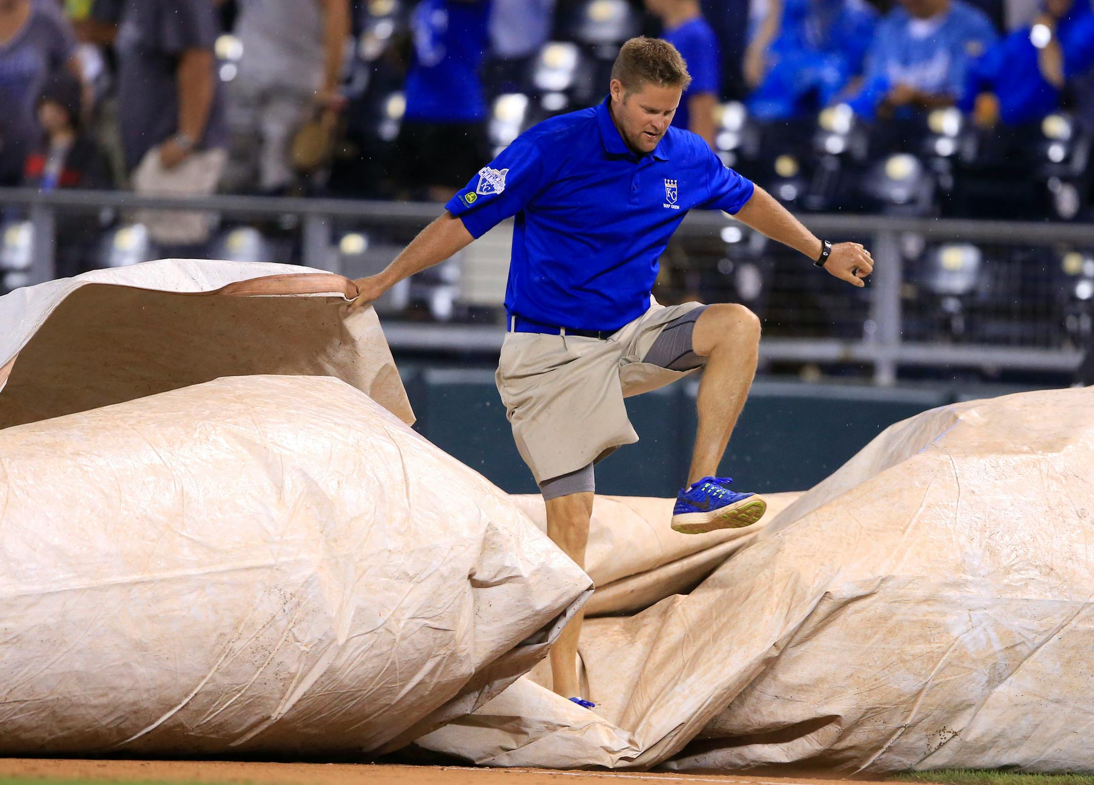 A grounds crew member works to cover the field during the fifth inning of a baseball game between the Kansas City Royals and the Minnesota Twins at Kauffman Stadium in Kansas City, Mo., Friday, Aug. 19, 2016. (AP Photo/Orlin Wagner)