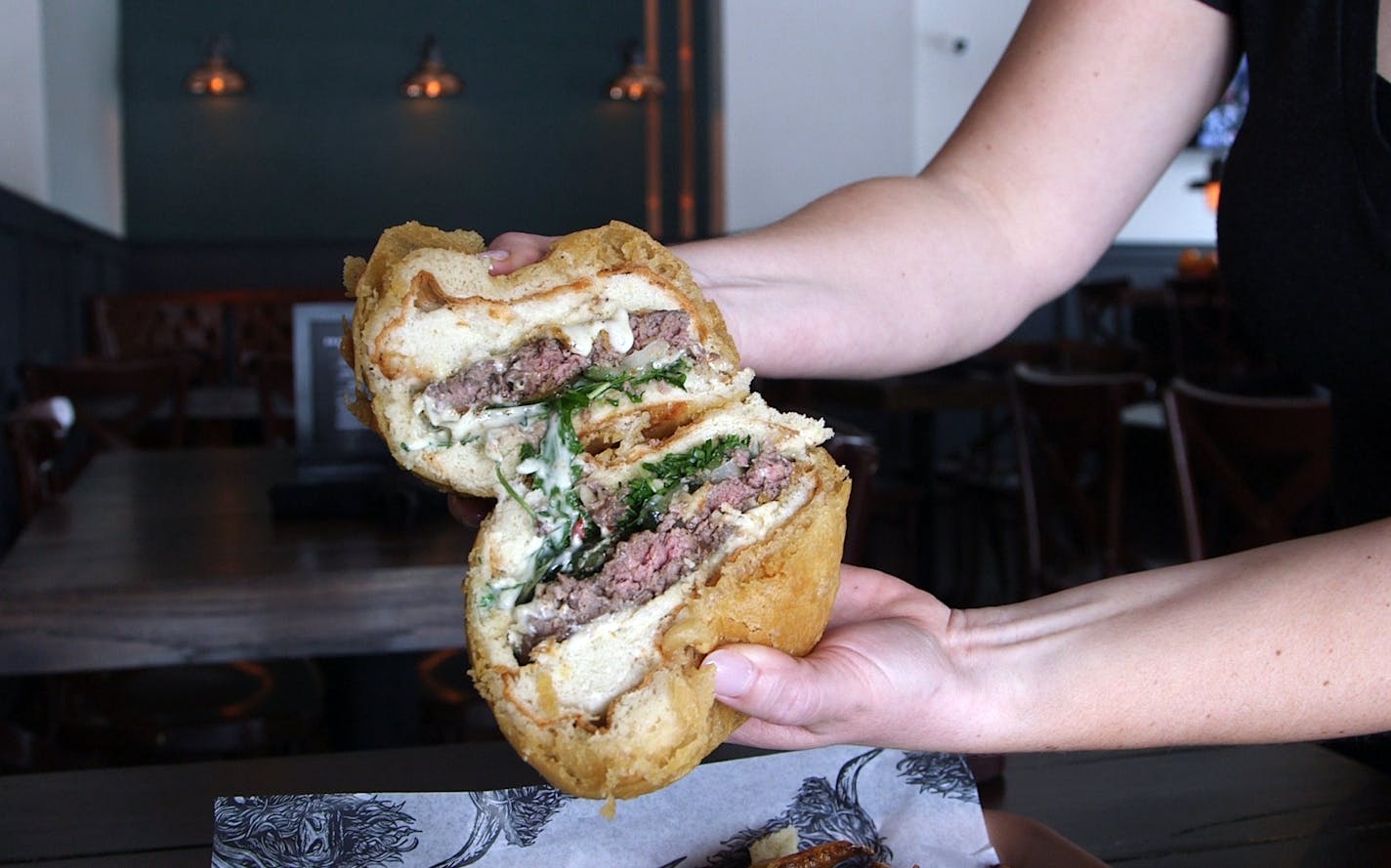 Copper Cow&#xd5;s deep-fried burger is a patty of ground TKcuts griddled to a rosy medium rare, slathered with oozing brie, set on a scratch-made bun, coated in tempura batter, fried, and stabbed through the heart with a giant steak knife. Copper Cow Bar & Kitchen in Minnetonka, Minnesota ] Matt Gillmer, matt.gillmer@startribune.com