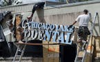 Workers remove the sign on June 23, 2020, at Ali Barbarawi's Chicago Lake Family Dental practice in Minneapolis, which was forced to close by the coro
