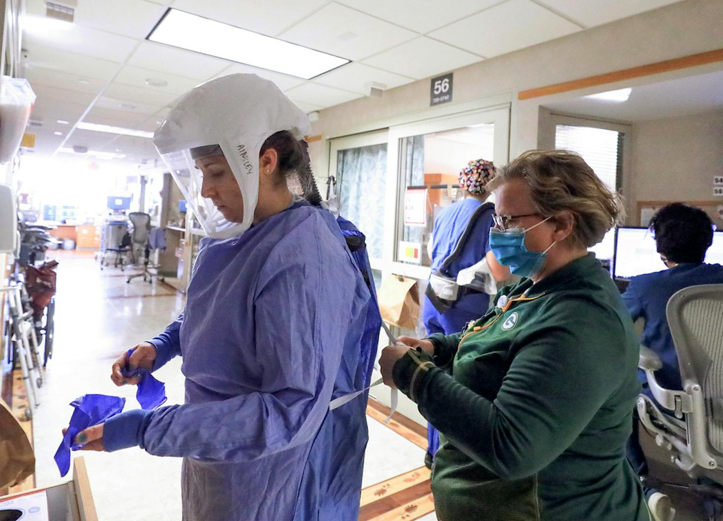 Deb Dalsing, nurse manager of the COVID-19 treatment unit at UW Health, assists nurse Ainsley Billesbach with her personal protective equipment at the hospital in Madison, Wis. Thursday, Nov. 5, 2020.