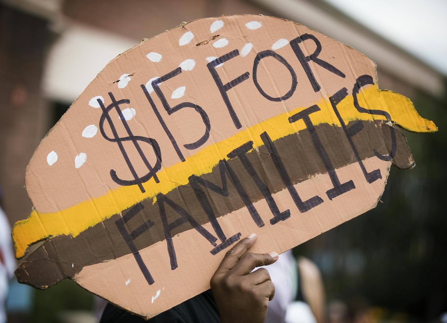 A man holds a sign shaped like a cheeseburger during a rally and march supporting $15 minimum wage on W. Broadway Avenue. ] (Leila Navidi/Star Tribune) leila.navidi@startribune.com BACKGROUND INFORMATION: Activists supporting a $15 minimum wage rally and march outside corporate fast food restaurants, payday lenders and a bank on W. Broadway Avenue in north Minneapolis on Monday, September 12, 2016. The activists are pushing for an ordinance passage at City Hall this year for a $15 minimum wage i