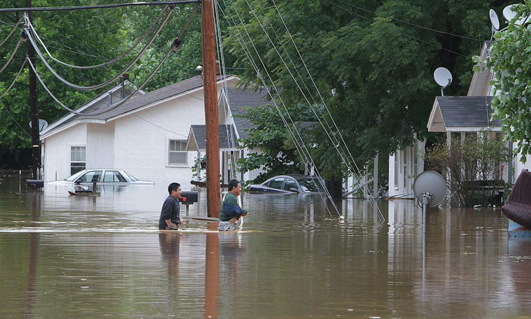 Jordann Lamborn and Jonathan Enriquez cross flooded Valley Rd. in Waynesville, Mo., on Tuesday.