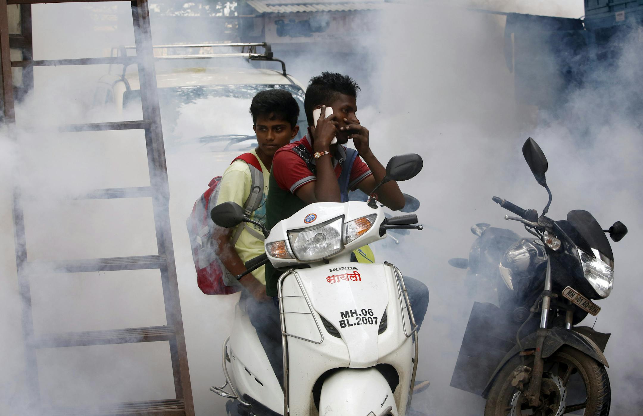 Indian boys sit on a scooter surrounded by smoke rising from fumigation to check the spread of mosquito-borne diseases, outside a train station in Mumbai, India, Saturday, Sept. 3, 2016. Scientists trying to predict the future path of Zika say that 2.6 billion people living in parts of Asia and Africa could be at risk of infection, based on a new analysis of travel, climate and mosquito patterns in those regions. Some of the most vulnerable countries include India, China, the Philippines, Indone