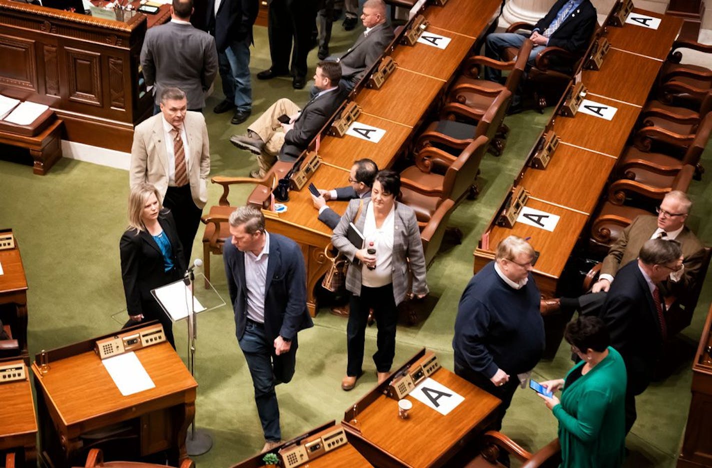 Desks and chairs where Minnesota Legislators were allowed to sit, were marked with a letter A, in order to keep them six feet away from each other, forcing some to sit in the visitors gallery and in the alcoves at the back of the chamber. On Monday they were all asked to be on call within an hours notice.