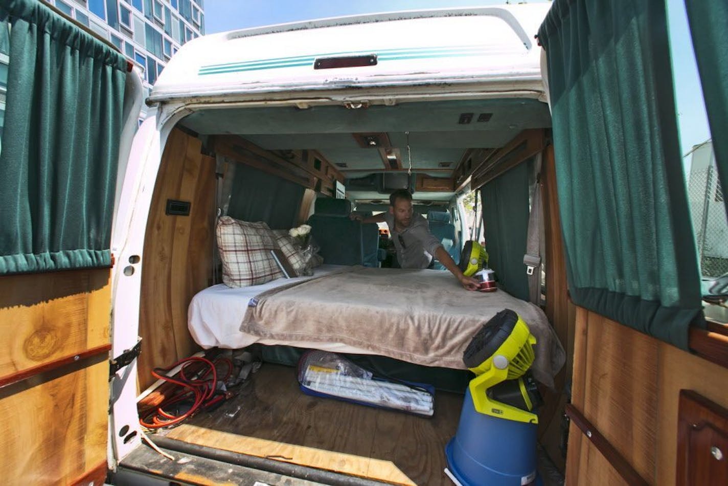 In this Monday, Aug. 3, 2015, photo, Jonathan Powley, who rents parked vehicles on Airbnb, prepares a 1995 Chevrolet conversion van, one of his offerings, in the Queens borough of New York. While parked vehicles make up only a fraction of the thousands of Airbnb listings in New York City, they provide an option for adventurous, budget-minded visitors seeking a place for far less than the $200-and-up most hotels charge.