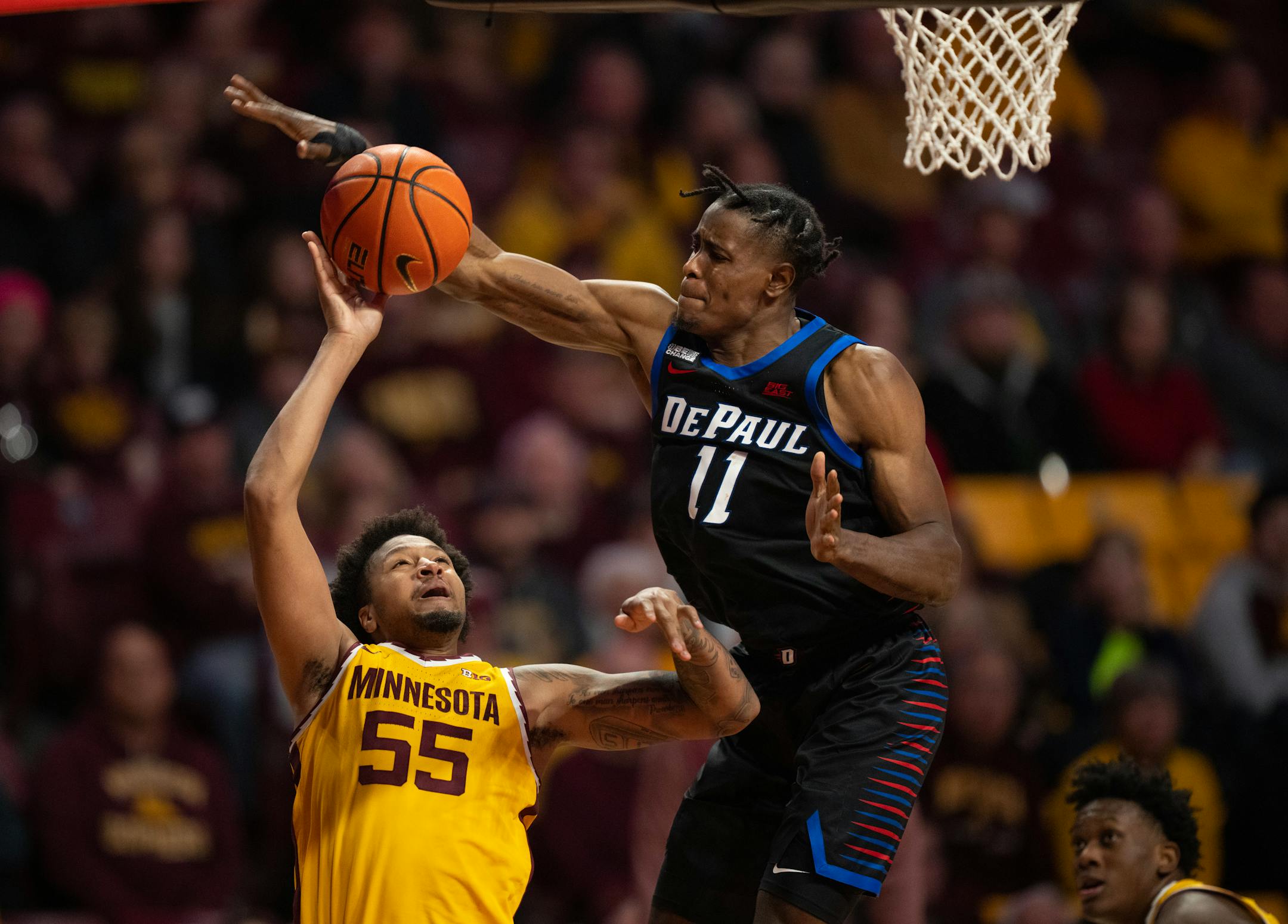 Minnesota Gophers guard Ta'lon Cooper (55) tried to get a shot off under the defense of DePaul Blue Demons forward Eral Penn (11) in the second half.