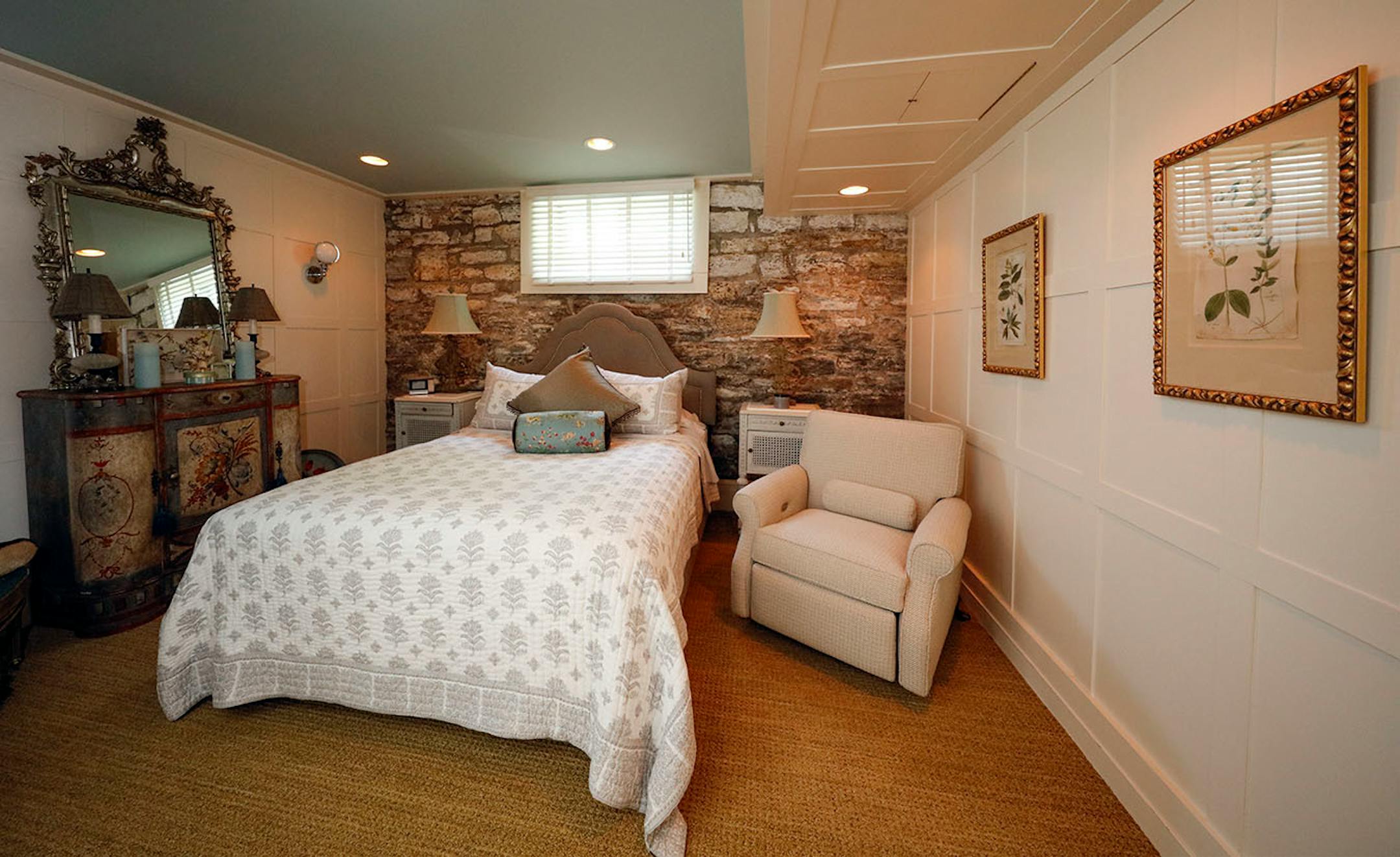 A bedroom on the lower level has an accent wall of exposed original stone.