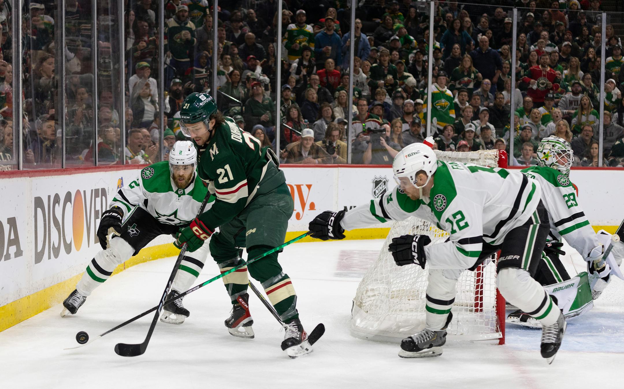 Minnesota Wild right wing Brandon Duhaime (21) tried to control the puck behind the Dallas net while defended by Dallas Stars defenseman Jani Hakanpää (2) and Dallas Stars center Radek Faksa (12) in the second period.