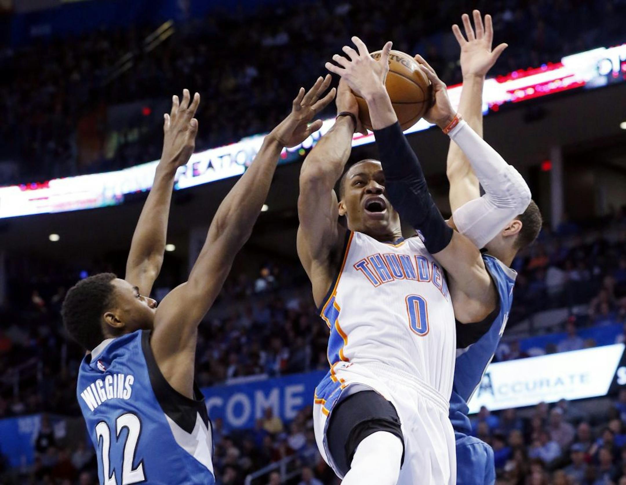 Oklahoma City Thunder guard Russell Westbrook (0) is fouled by Minnesota Timberwolves guard Zach LaVine, right, as he shoots between LaVine and forward Andrew Wiggins (22) in the fourth quarter of an NBA basketball game in Oklahoma City, Monday, Jan. 26, 2015. Oklahoma City won 92-84.