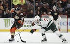 Anaheim Ducks left wing Kevin Roy, left, moves the puck defended by Minnesota Wild right wing Nino Niederreiter during overtime of an NHL hockey game 