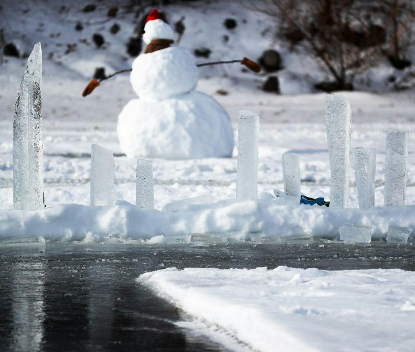 Chuck Zwilling and his crew worked on cutting the ice for their giant floating ice carousel -- more than 130 meters across -- on Green Prairie Fish Lake, using a custom rig that combines tracks from a snowblower and two chainsaws Thursday, Jan. 10, 2019, in Little Falls, MN. Here, ice chunks cut from the lake to create the channel for the ice carousel to turn are stacked with a snowman looming in the rear.