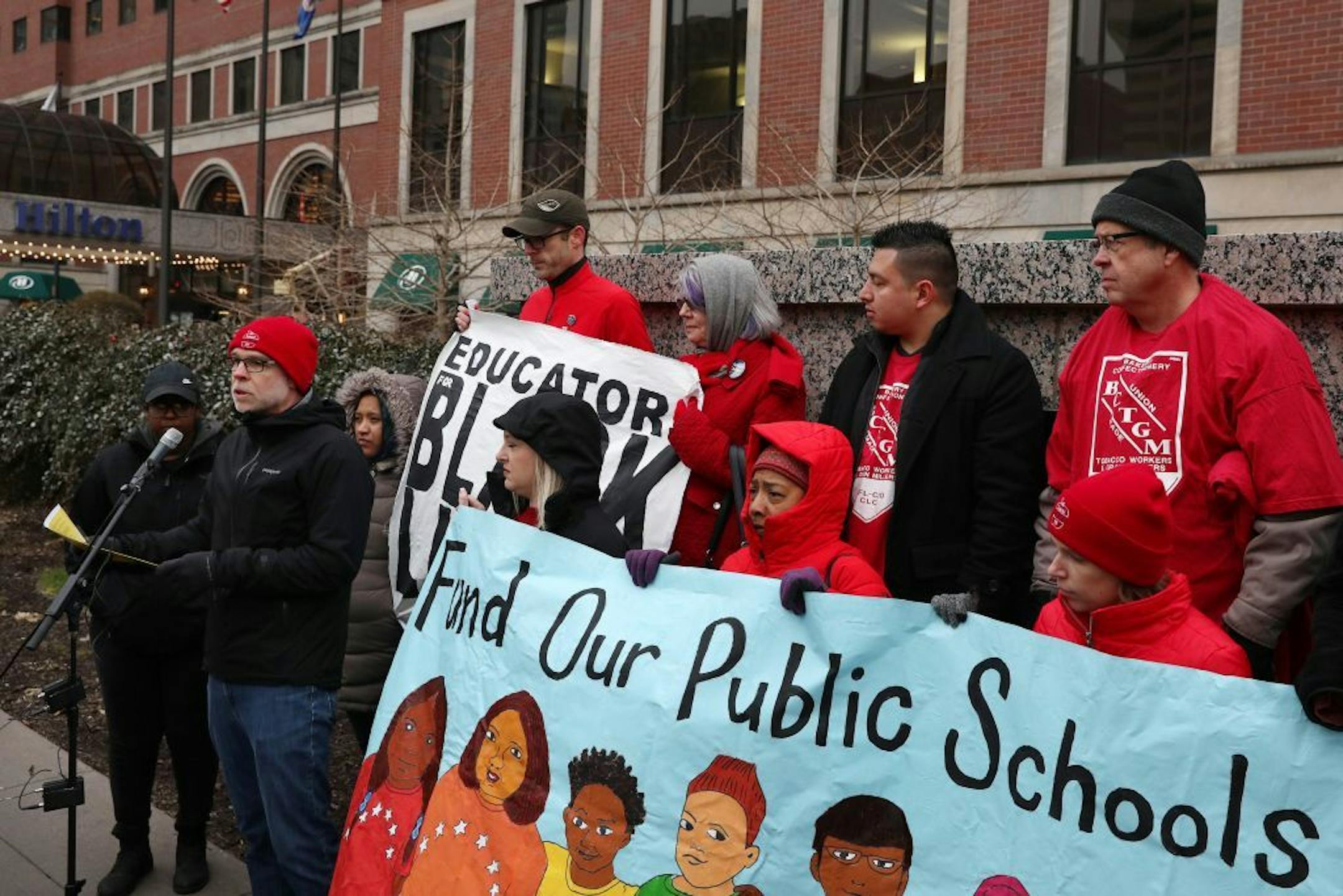 Nick Faber, president of the St. Paul Federation of Teachers, spoke as others held signs while they protested at a CEO luncheon outside the Hilton hotel.
