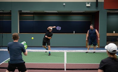 Jerry Baack, CEO of Bridgewater Bank, returned a shot as he and Alex Bisanz played a match against Tony Ferraro, left, and Katie Morrell at the Minnea