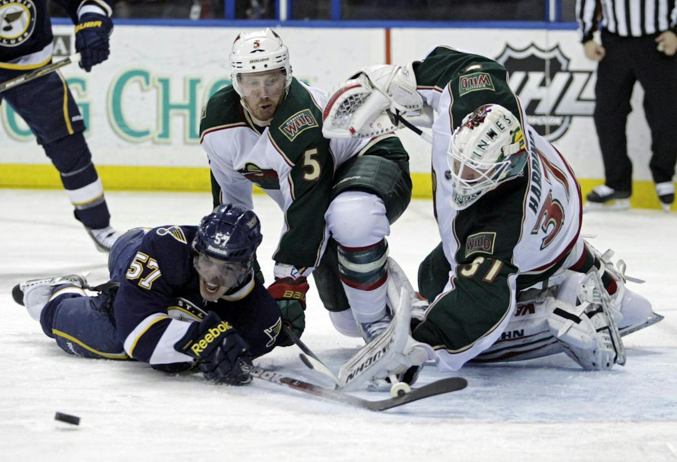 St. Louis Blues' David Perron (57) tries to direct the puck into the net while falling down as Minnesota Wild goalie Josh Harding (37) and Greg Zanon (5) defend in the second period of an NHL hockey game, Saturday, Feb. 18, 2012 in St. Louis.