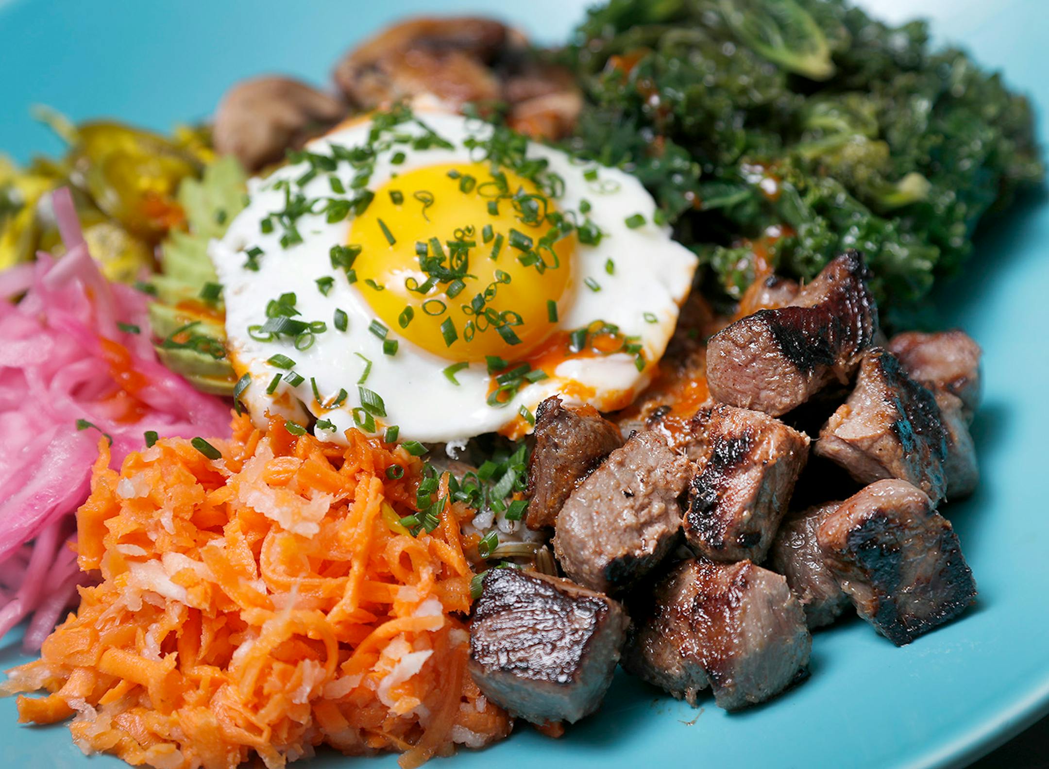 Bi Bim Bap. Cilantro lime wild rice and Korean BBQ sauce, marinated kale, pickled jalapenos, brined onions, marinated flank steak, saut�ed mushrooms and daikon carrot slaw topped with a sunny side egg and scallions at The Duluth Grill.