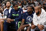 Minnesota Timberwolves players Kyle Anderson (from left), Nathan Knight, Naz Reid, and Jordan McLaughlin sit on the bench during the first half of an 