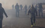 Migrants run from tear gas launched by U.S. agents, amid photojournalists covering the Mexico-U.S. border, after a group of migrants got past Mexican 