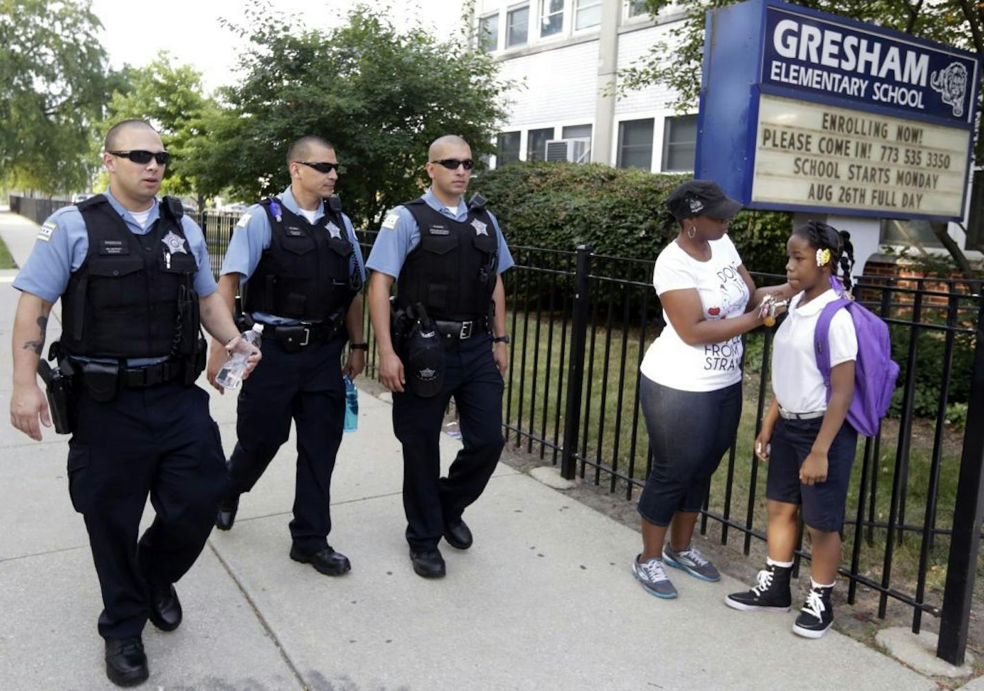 Chicago Police patrol the neighborhood as Crystal Stoval delivers her niece Kayla Porter from their south side home to Gresham Elementary School on the first day of classes Monday, Aug. 26. 2013 in Chicago.