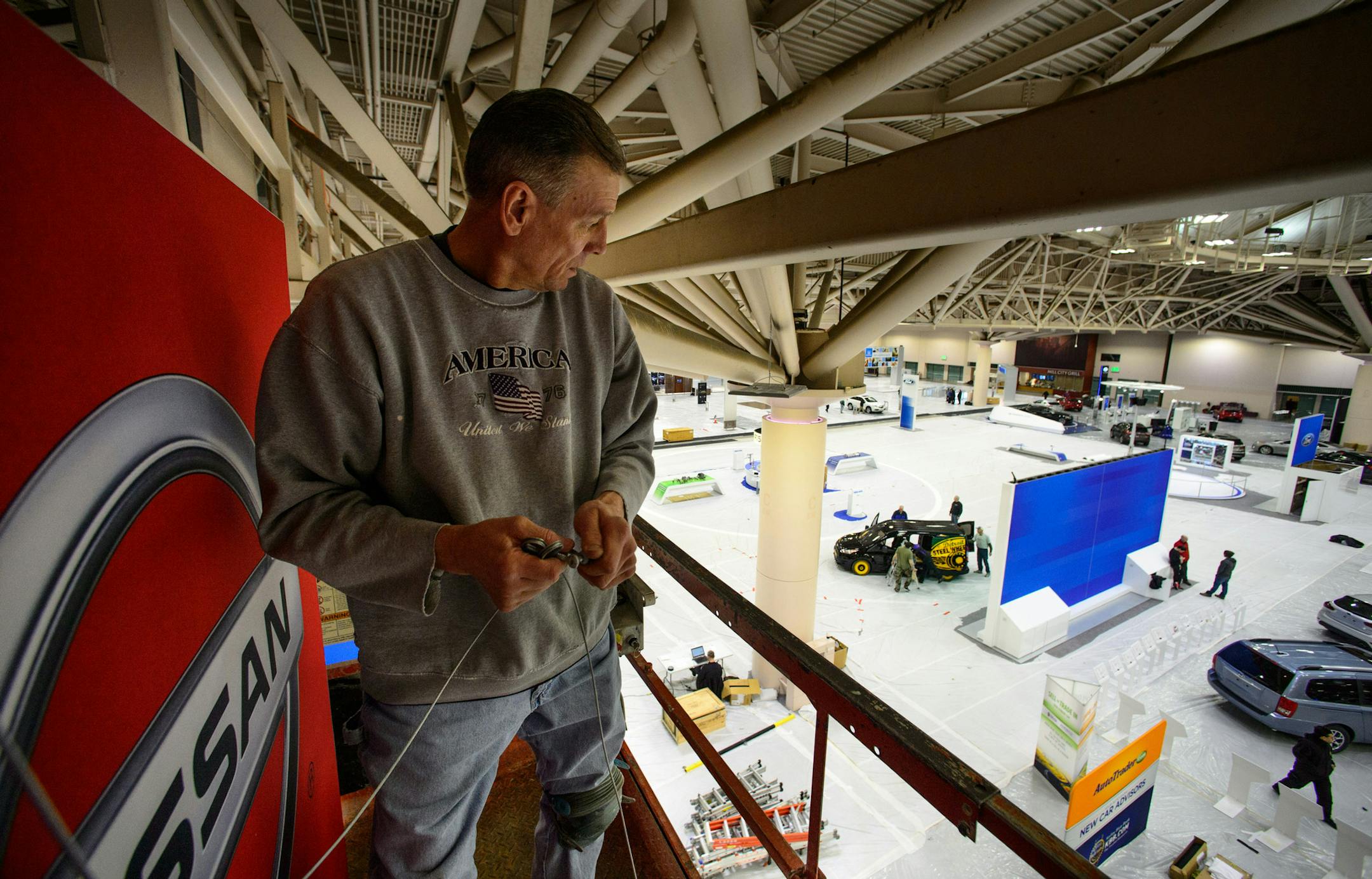 Scott Nehring hung signs from the convention center ceiling for the Twin Cities Auto Show which runs through March 16. ] GLEN STUBBE * gstubbe@startribune.com Friday March 7, 2014
