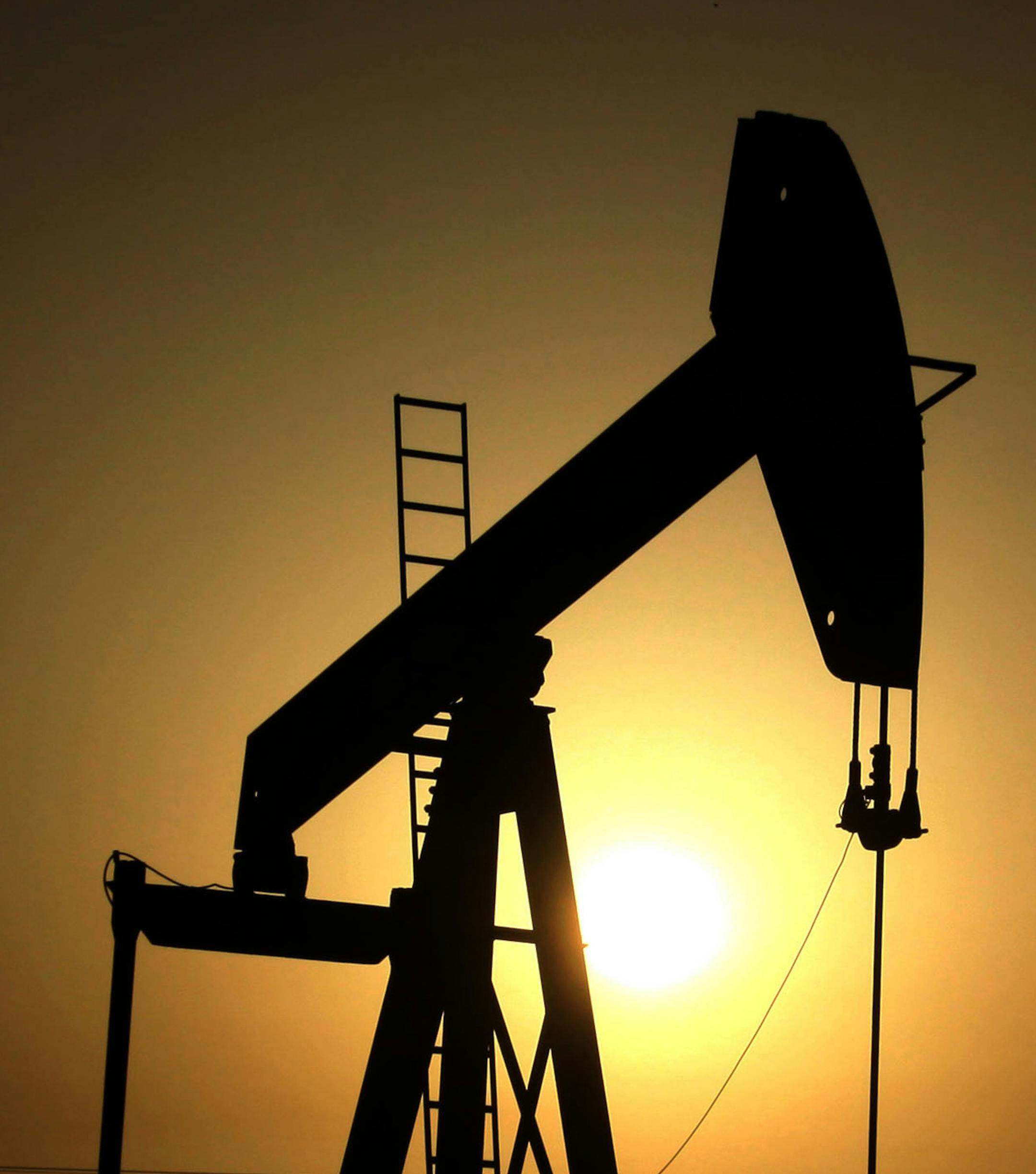 FILE- In this Wednesday, June 8, 2011 file photo, sun sets behind an oil pump in the desert oil fields of Sakhir, Bahrain. OPEC nations have agreed in theory that they need to reduce their production to help boost global oil prices during a meeting in Algeria, but a major disagreement between regional rivals Saudi Arabia and Iran still may derail any cut. (AP Photo/Hasan Jamali, File)