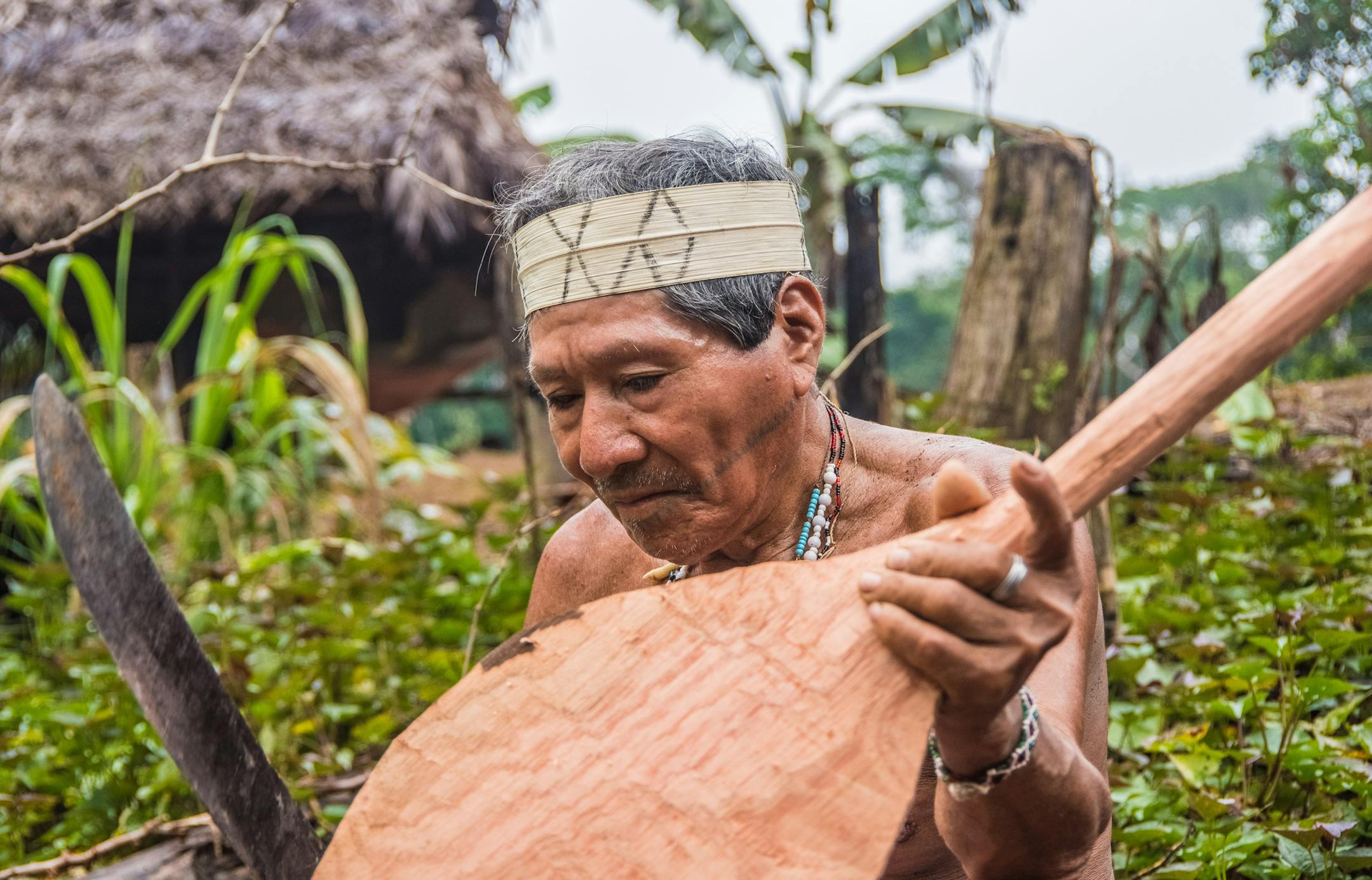 A Mats&#x17d;s elder uses his machete to whittle an oar. Tumi, a Mats&#x17d;s elder, uses his machete to whittle an oar for a pair of young newlyweds who lack his expertise. The traditional knowledge stored in the minds of Mats&#x17d;s elders is often sought by the next generation, but not adopted by the next generation.