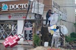 Residents clean up the entrance of a drugstore damaged by Hurricane Beryl in Tulum, Mexico, Friday, July 5, 2024. (AP Photo/Fernando Llano)