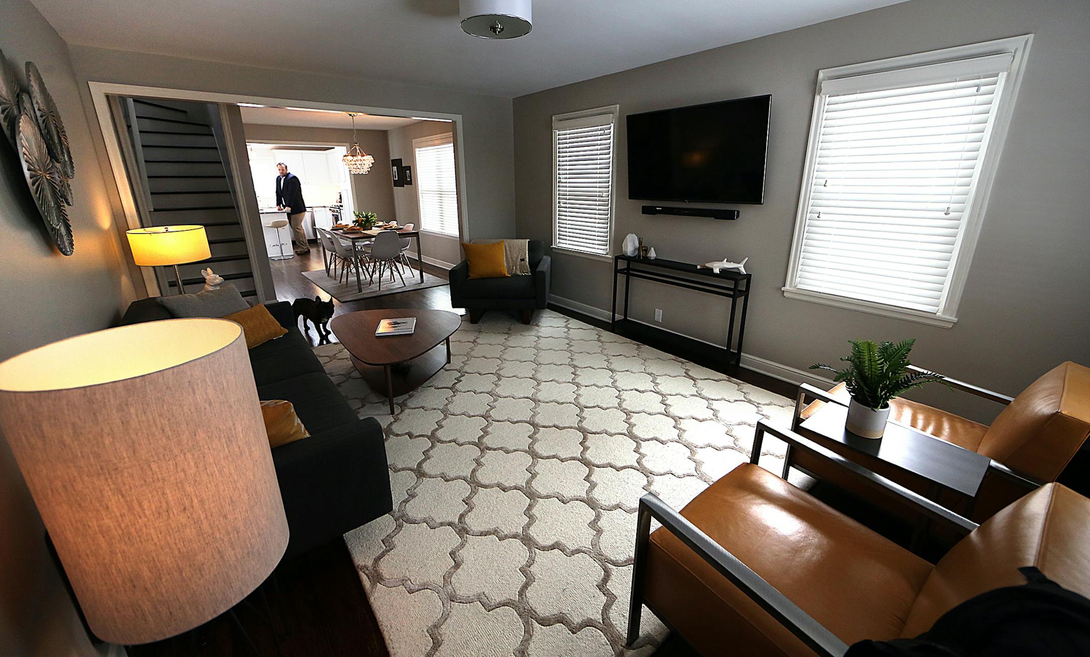 The living room is furnished with a smoke-hued sofa and camel-colored chairs.