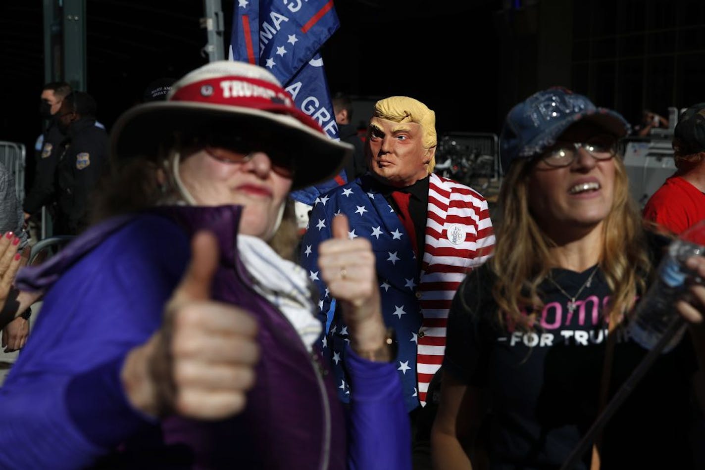 A demonstrator wears a mask of President Donald Trump while standing with others outside the Pennsylvania Convention Center where votes are being counted, Friday, Nov. 6, 2020, in Philadelphia.