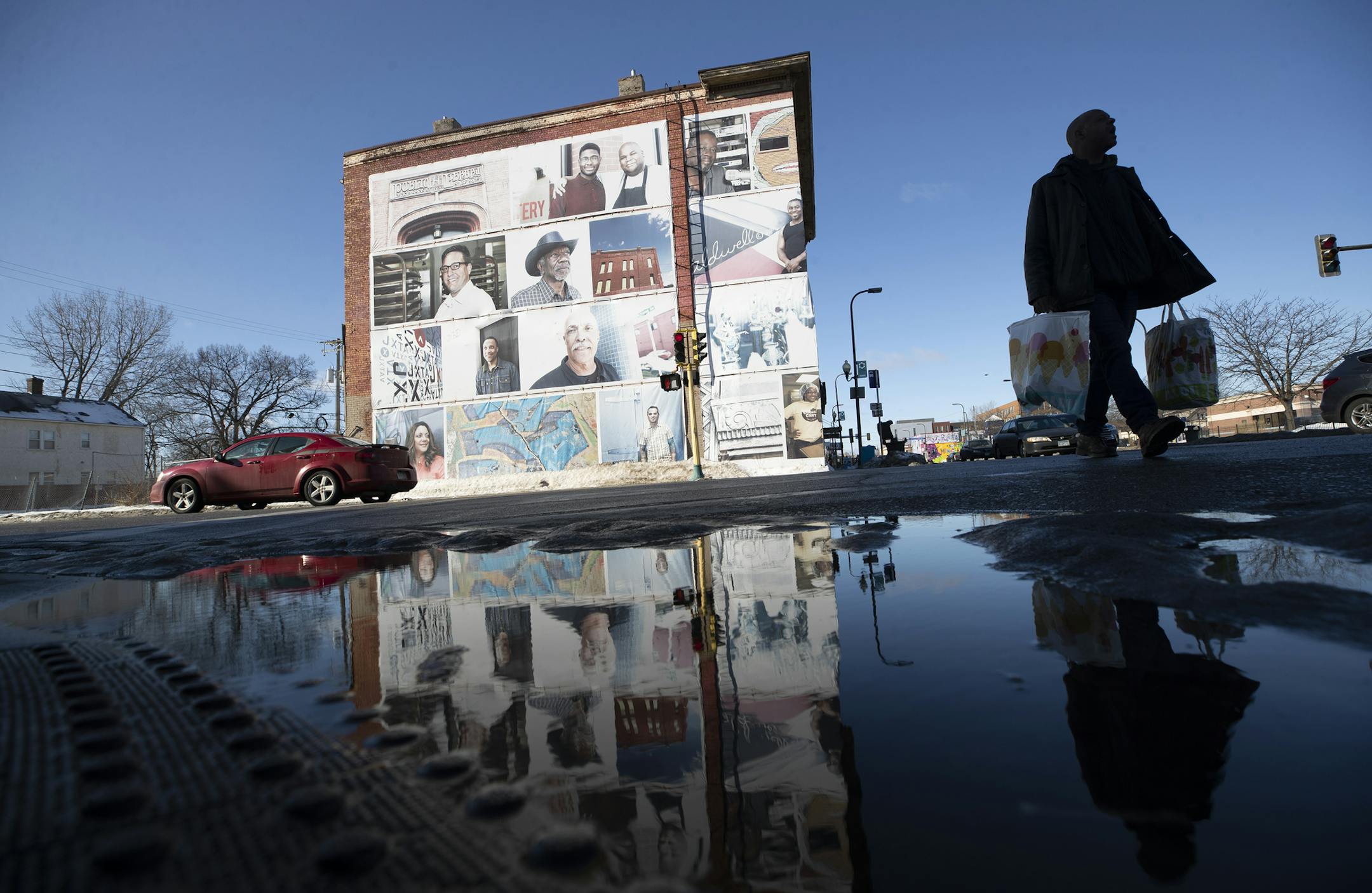 A pedestrian navigated around the puddles past a building that was reflected in the water from melted snow at Dupont and Broadway Avenue on Sunday morning in North Minneapolis. ] Jerry Holt • Jerry.Holt@startribune.com The 46 degree weather melted some ice and snow Sunday morning , February 2, 2020 in North Minneapolis .