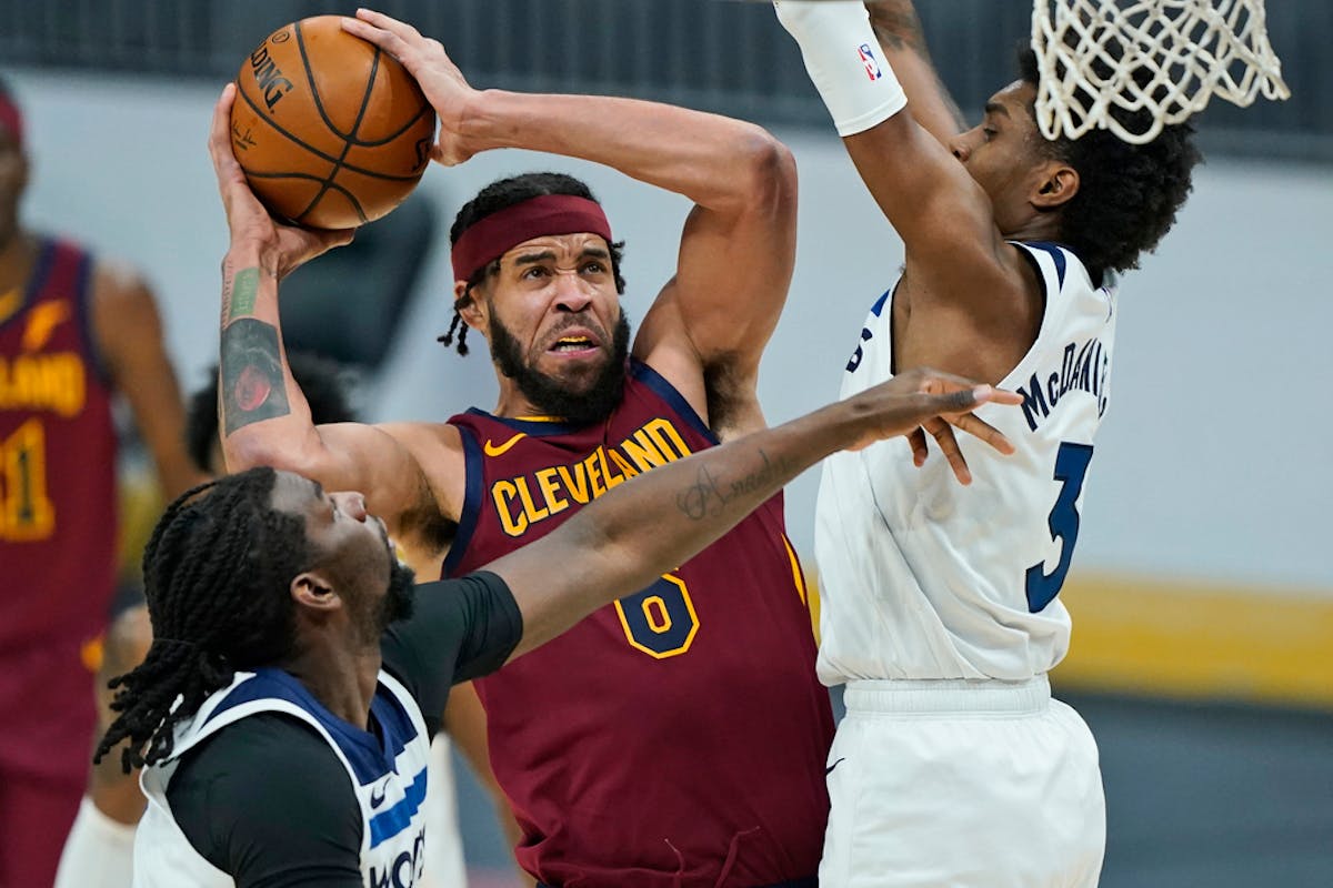 Cleveland Cavaliers' JaVale McGee, center, drives to the basket against Minnesota Timberwolves' Naz Reid, left, and Jaden McDaniels , right.