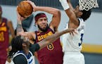 Cleveland Cavaliers' JaVale McGee, center, drives to the basket against Minnesota Timberwolves' Naz Reid, left, and Jaden McDaniels , right.