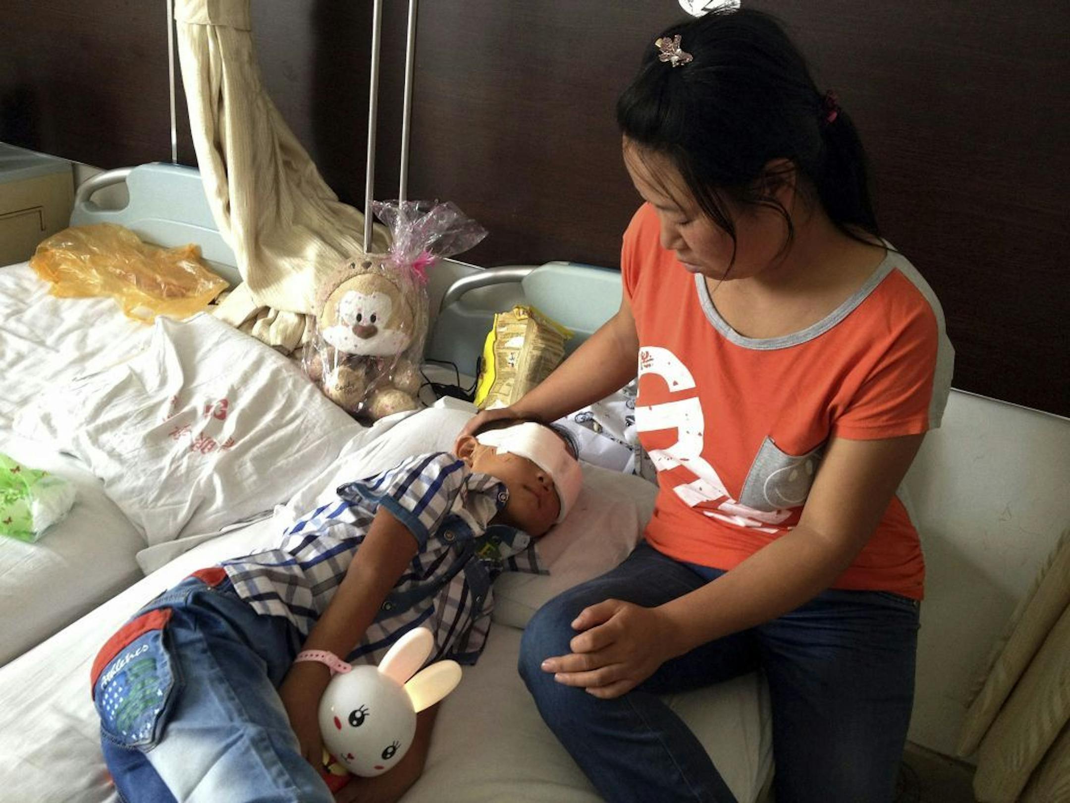 Guo Bin recuperates near his mother from an attack in the rural area of Linfen city that left him blind in a hospital in Taiyuan in northwest China's Shanxi province on Wednesday, Aug. 28, 2013.