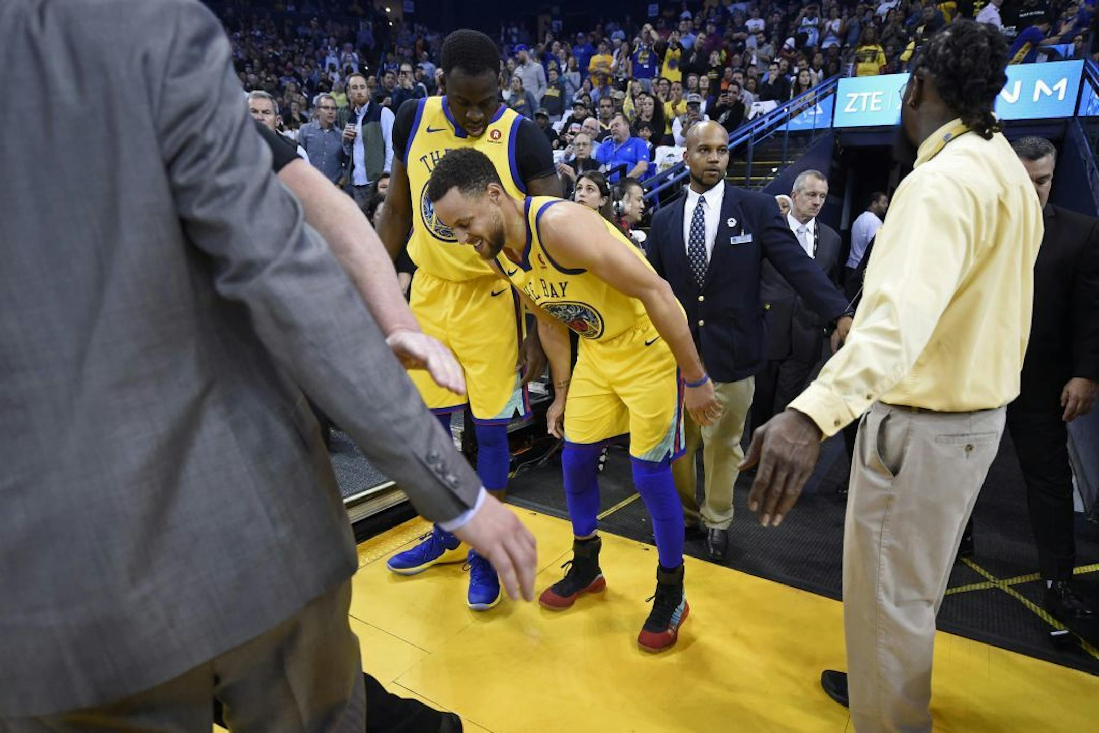 Golden State Warriors' Stephen Curry (30) limps back to the court after injuring his right ankle as teammate Draymond Green (23) checks on his condition during the first quarter of their NBA game at the Oracle Arena in Oakland, Calif., on Thursday, March 8, 2018. The Warriors won, 110-107.