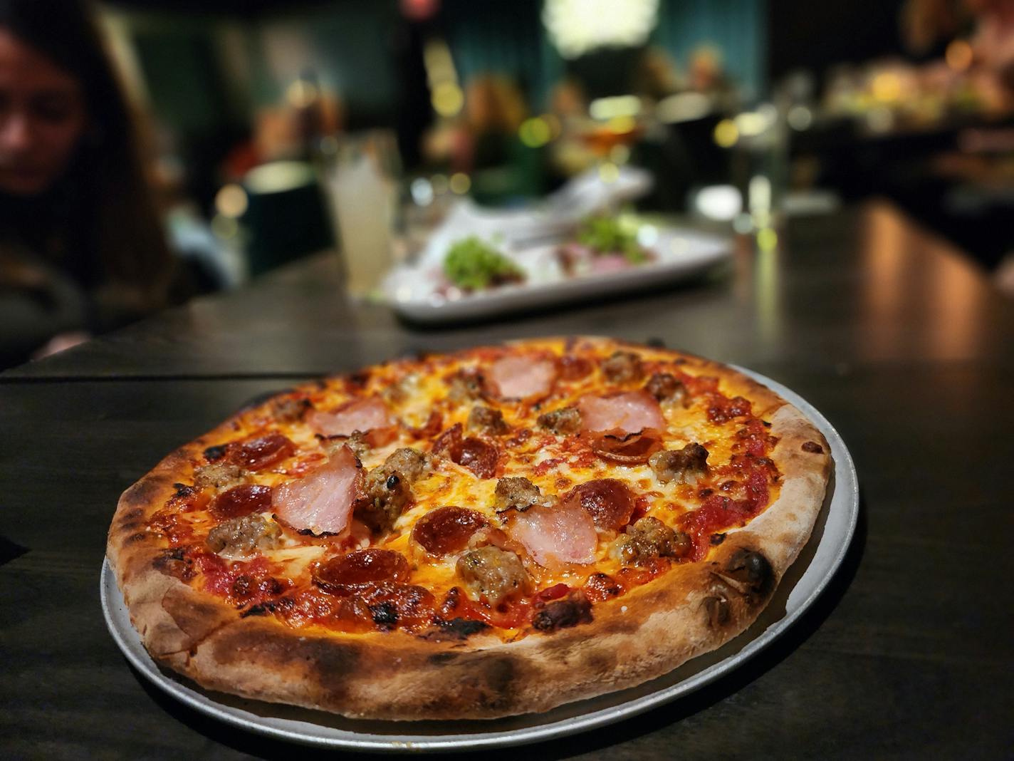 A pizza topped with different cuts of cured meat