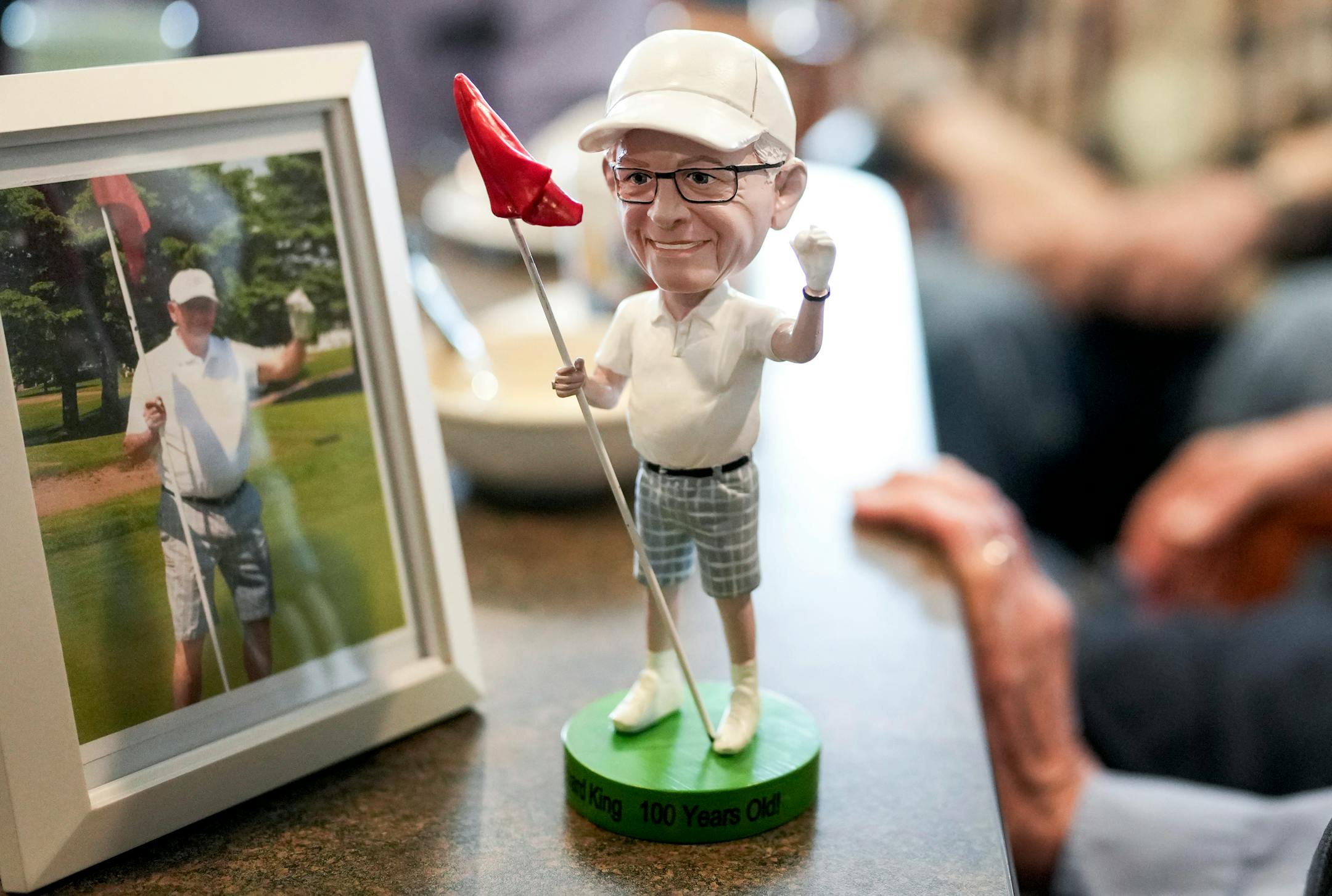 Richard King showed a custom made bobblehead inspired from a picture of him after scoring a hole-in-one he got as a gift from his daughter for his 100th birthday while celebrating with fellow residents and staff at his home New Perspective Woodbury senior facility in Woodbury, Minn., on Thursday, June 8, 2023.