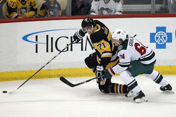 Pittsburgh Penguins' Evgeni Malkin (71) and Minnesota Wild's Mikael Granlund (64) battle for the puck during the first period of an NHL hockey game in