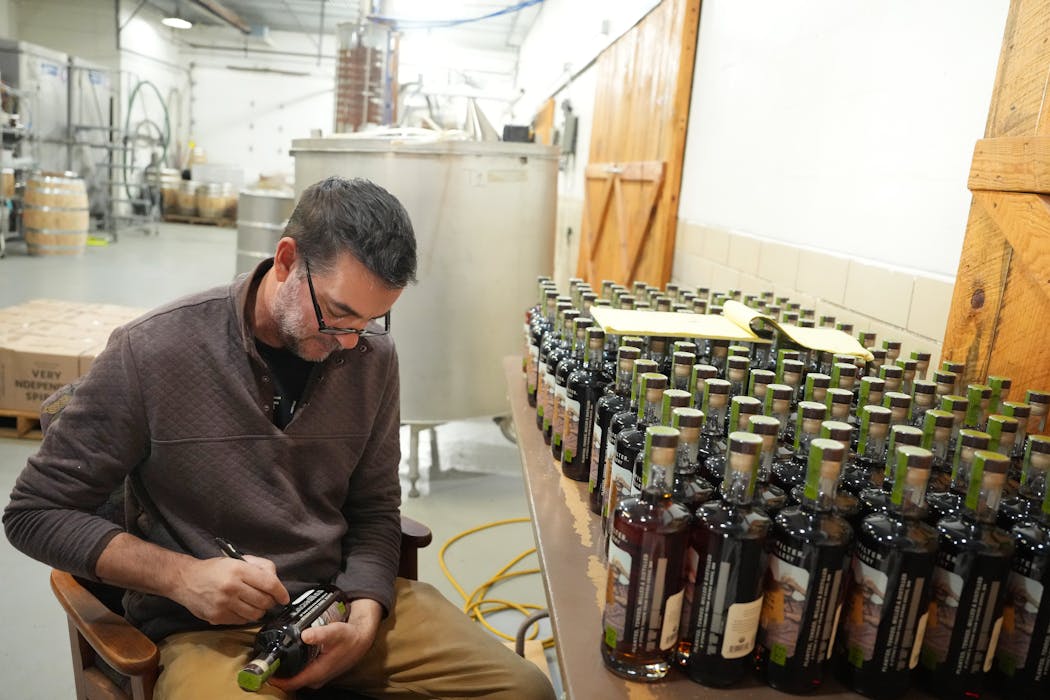 Christian Myrah, owner and founder of RockFilter Distillery, signs bottles of whisky, something he does for every bottle.