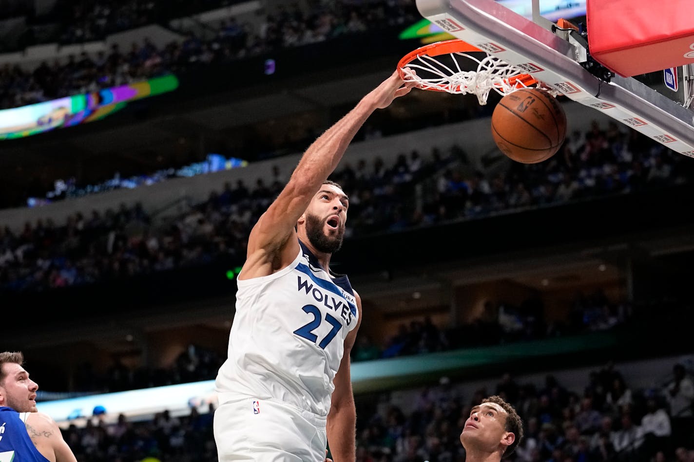 Minnesota Timberwolves center Rudy Gobert (27) dunks over Dallas Mavericks' Dwight Powell, right, as Luka Doncic, left, looks on in the first half of an NBA basketball game, Monday, Feb. 13, 2023, in Dallas. (AP Photo/Tony Gutierrez)