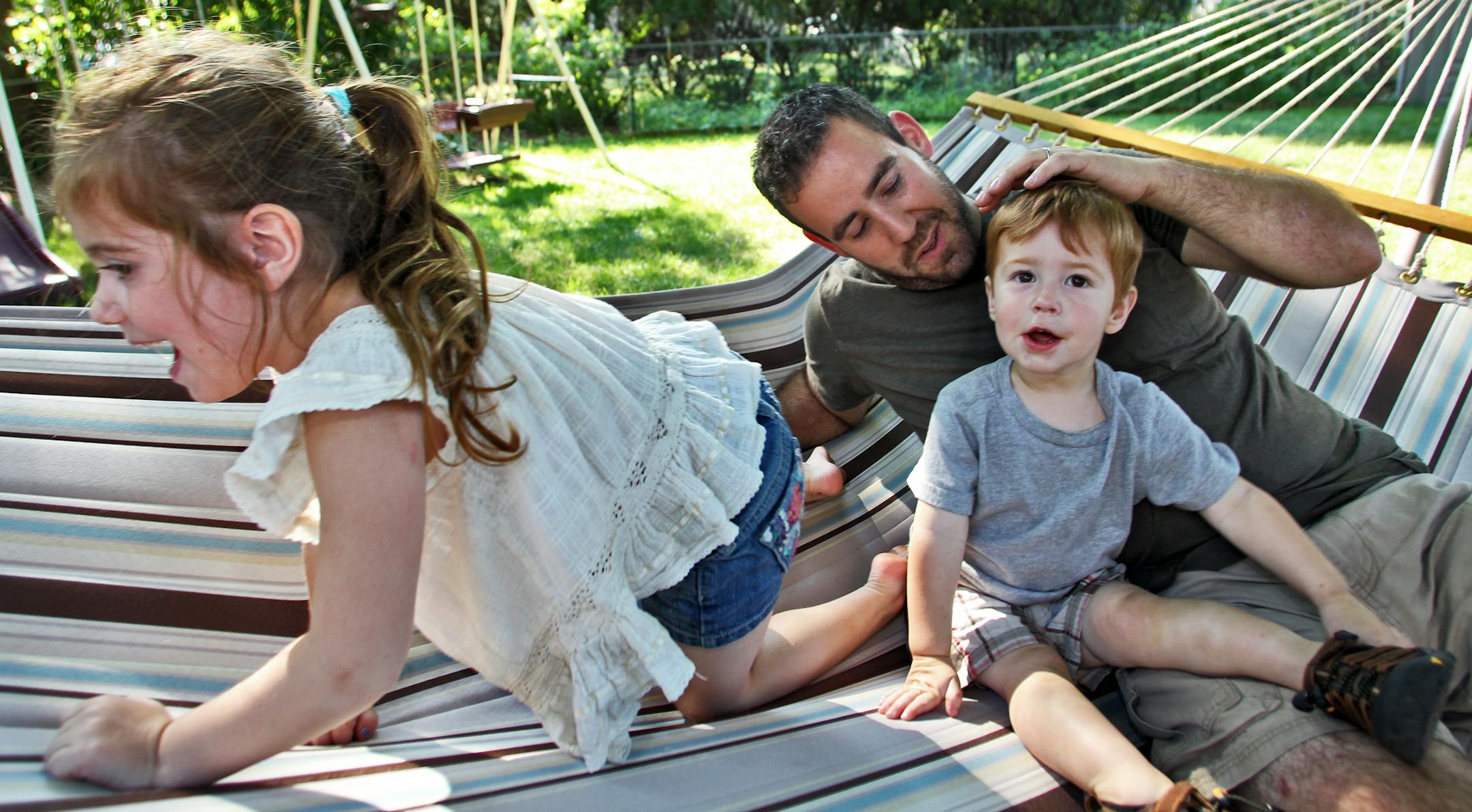 Zachary Moore is a stay-at-home dad who takes care of his family's two children Rossalyn Moore, 5, and Angus Moore, 1, in their St. Louis Park home while his wife works a job away from the house. Zachary with Rossalyn and Angus in backyard hammock. (MARLIN LEVISON/STARTRIBUNE(mlevison@startribune.com (cq Rossalyn Moore, Angus Moore, Zachary Moore)