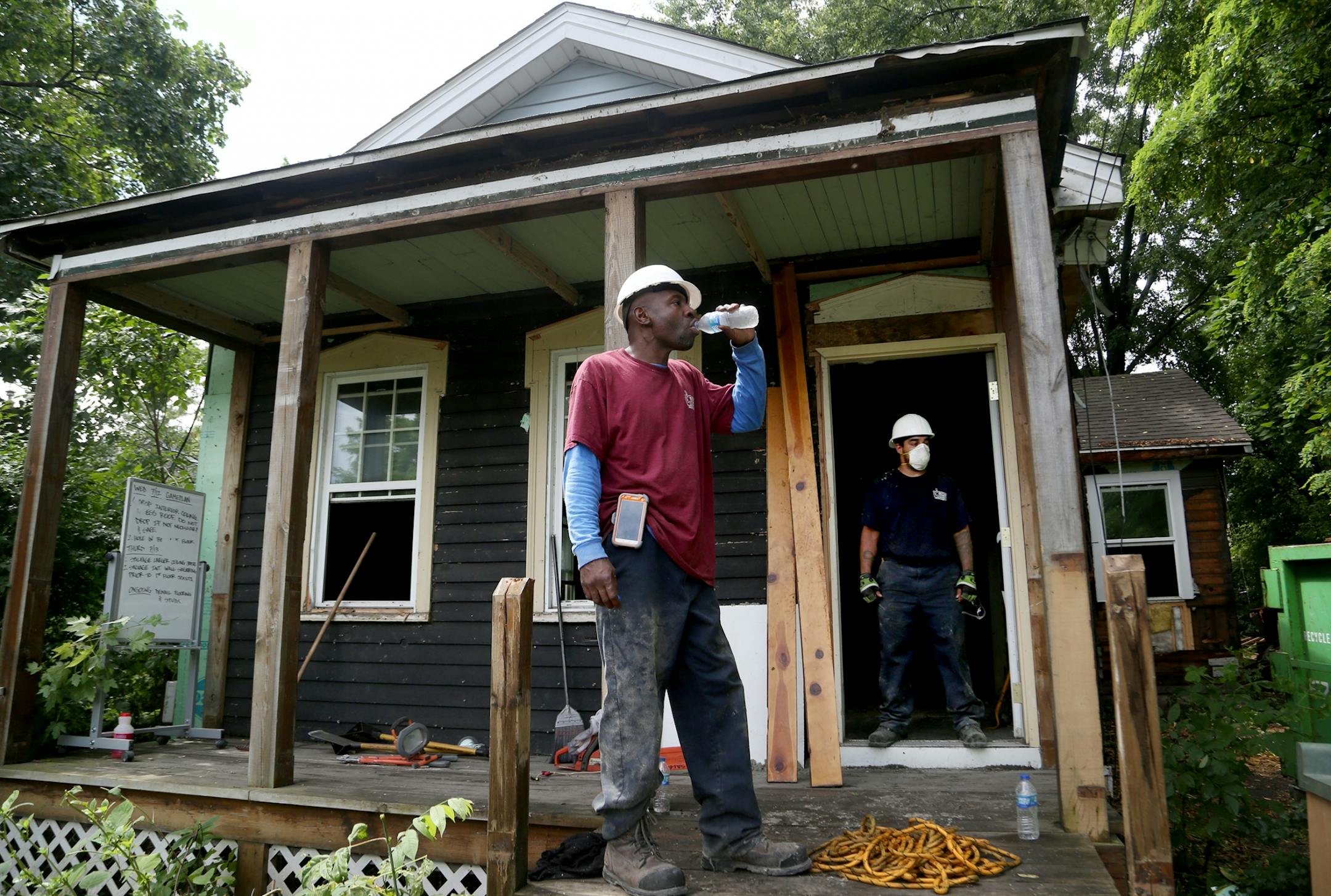 Fred Gurley, crew chief for Better Homes Minnesota, a non-profit that assists men in the community in gaining employment while helping protect the environment, takes a drink of water while breaking from disassembling a home as Josh Stewart, crew-chief-in-training, stands in the doorway Tuesday, July 18, 2017, in Roseville, MN.