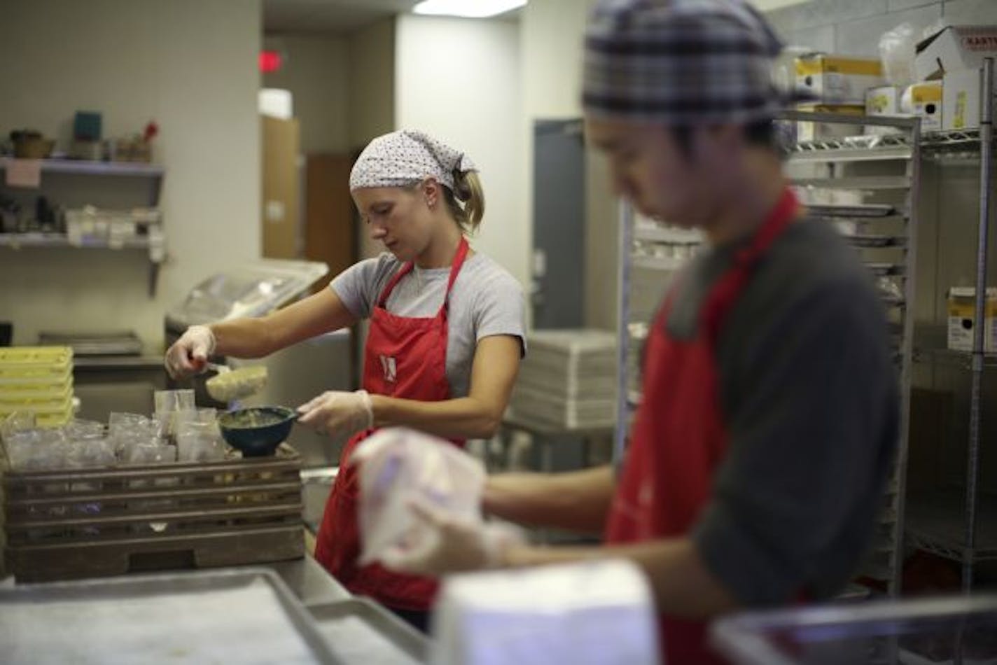 Kristen Dammann, a graduate student in nutrition at the University of Minnesota, volunteered at Open Arms in Minneapolis by packaging servings of beer cheese soup. In the foreground, Miles Hang packed cookies. The food is for HIV/AIDS patients.