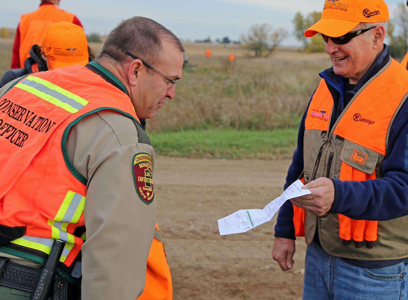 DNR conservation officer Lt. Gary Nordseth checks Gov. Mark Dayton's license before he went afield Saturday, first day of the 2017 ringneck season.