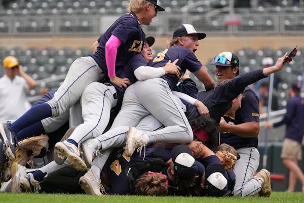 Totino-Grace’s Tommy Heifort (20) is mobbed by his teammates after getting the final out in the seventh inning of the 3A baseball championship game 