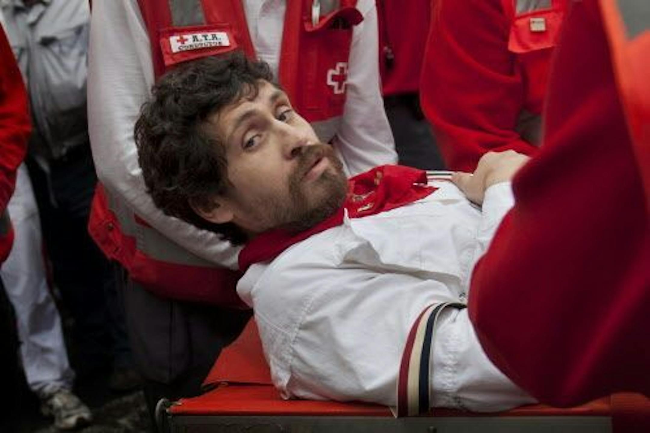 U.S. runner Bill Hillmann, 35, from Chicago, Ill., is carried on a stretcher after being gored on his right leg by a Victoriano del Rio ranch fighting bull during the running of the bulls at the San Fermin festival in Pamplona, Spain, Wednesday, July 9, 2014.