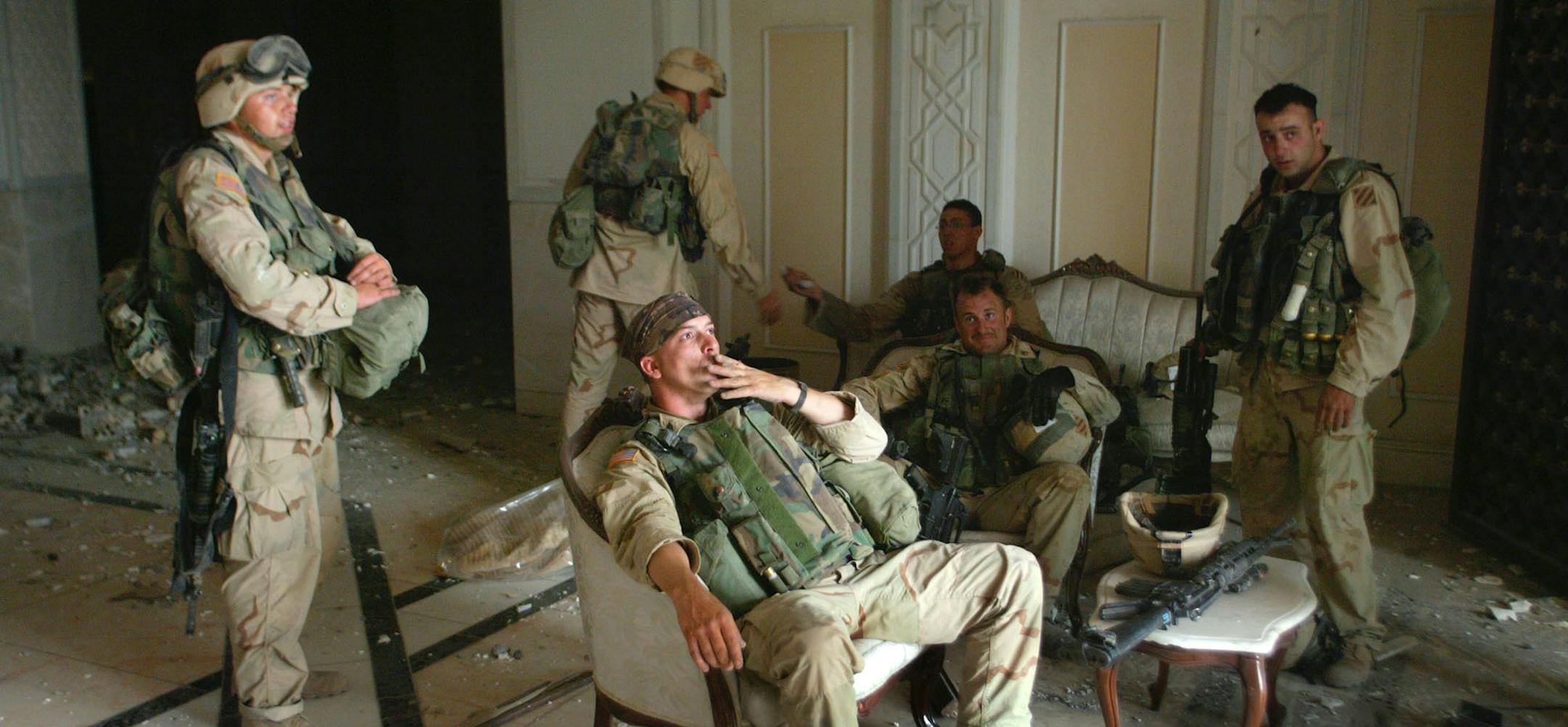 FILE - U.S. Army Stf. Sgt. Chad Touchett, center, relaxes with comrades from A Company, 3rd Battalion, 7th Infantry Regiment, after a search of one of Saddam Hussein's bomb-damaged palaces in Baghdad on Monday, April 7, 2003. (AP Photo/John Moore, File)