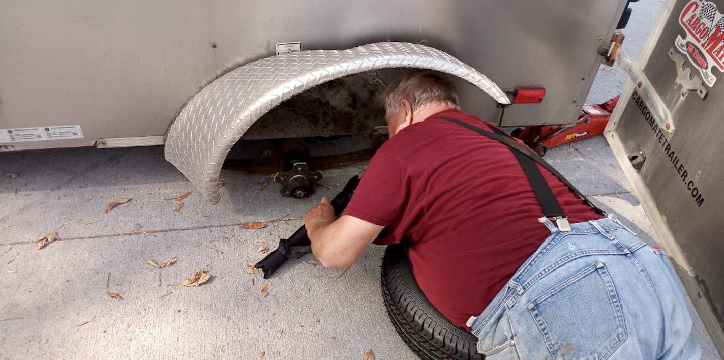 Will Ammermann fixes a tire on the trailer of Arvis Stubbs in Raymond, Minn.